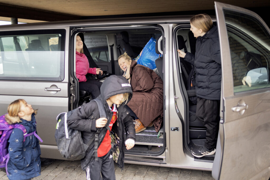 Line Myrup Sørensen i sin handicapbil med sine tre børn og hjælperen Anne-Sofie Bækgaard.