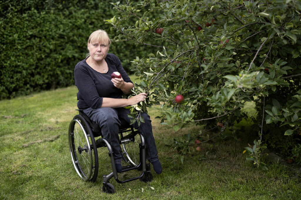 Eva Christensen plukker æbler fra sin kørestol